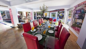 Ein Essbereich mit einem Glastisch, gedeckten Plätzen für sechs Personen, roten Sitzmöbeln und einer Kristallleuchtre.