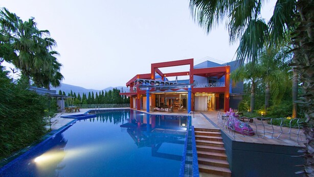 Ein modernes Haus mit Schwimmbad, einer überdachten Terrasse und einer Treppe zu einer Außenterrasse.
