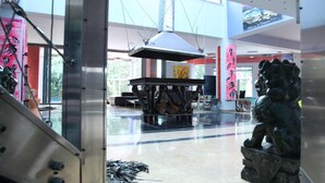 Eine geräumige Lobby mit modernem Industriedesign, inklusive eines großen Tisches, einer Skulptur und einem großen Fenster, das für natürliches Licht sorgt.