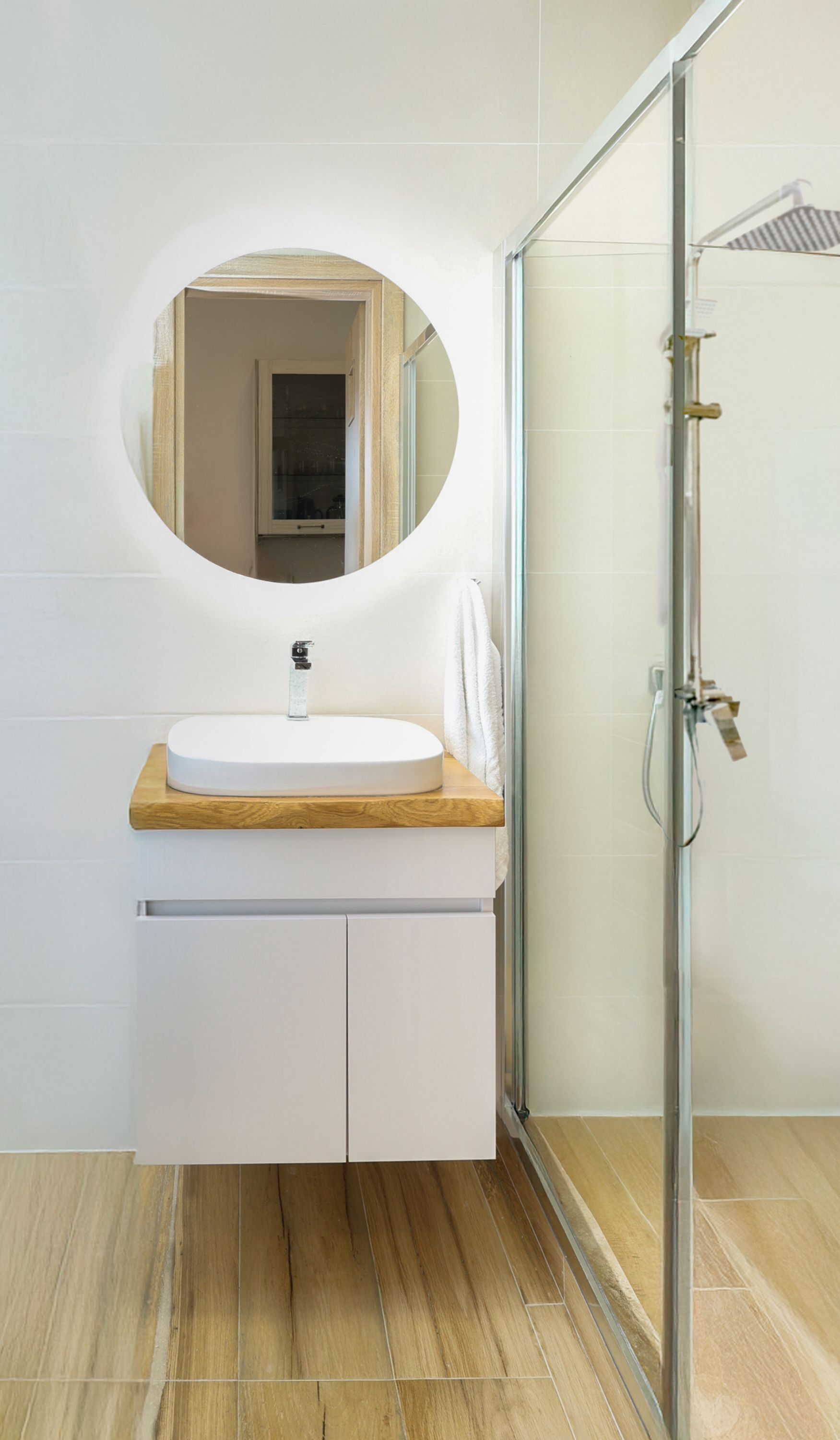 Ein Badezimmer mit rundem Spiegel, Waschbecken und Dusche.