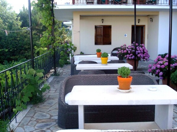 An outdoor seating area with wicker furniture and potted plants.