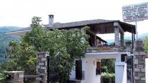 Edifici de pedra amb entrada coberta i un rètol que indica que és una propietat de lloguer, amb vista al paisatge circumdant.