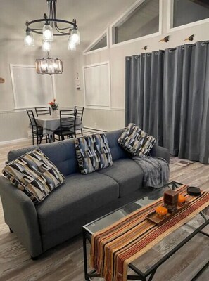 Relax in this stylish living room with a sofa, coffee table, and chandelier.