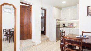 A compact kitchen with white cabinets, a wooden dining table, and chairs. - Karnagio Seafront in Agria (Volos)