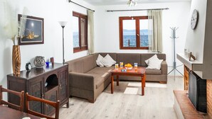 Una sala de estar con un sofá, una mesa de centro, un televisor y vista al mar a través de una ventana.