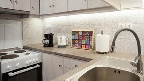Una cocina moderna con estufa, cafetera, tostadora y un colorido revoque de azulejos.