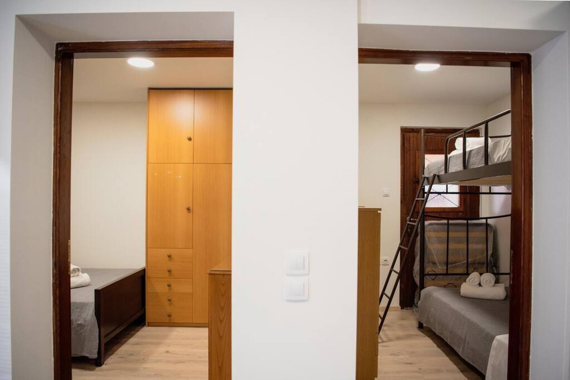 A bedroom with a wooden wardrobe, a bed, and a bunk bed.