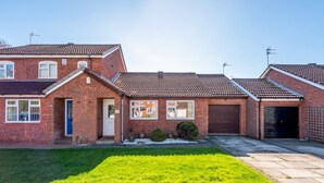 A two-story brick house with a tiled roof, a front garage, and a well-maintained lawn.
