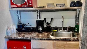 A compact kitchen with a red microwave, a coffee maker, and a sink. - Scenic Valley Motel (Lansing)