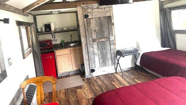 A compact room with two beds, a kitchenette, and a TV mounted on the wall. - Scenic Valley Motel (Lansing)