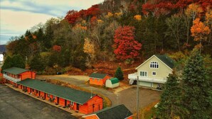 A row of red cabins with a white house in the background, surrounded by autumn foliage. - Scenic Valley Motel (Lansing)