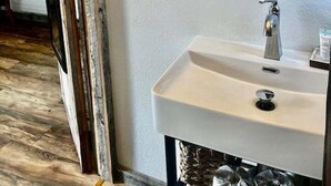 A bathroom with a white sink, a mirror, and a wooden door frame. - Scenic Valley Motel (Lansing)