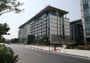 A multi-story hotel with a modern architectural design, featuring balconies on each floor and a parking area in front. - Nasma Luxury Stays - One Park Avenue (Dubai)