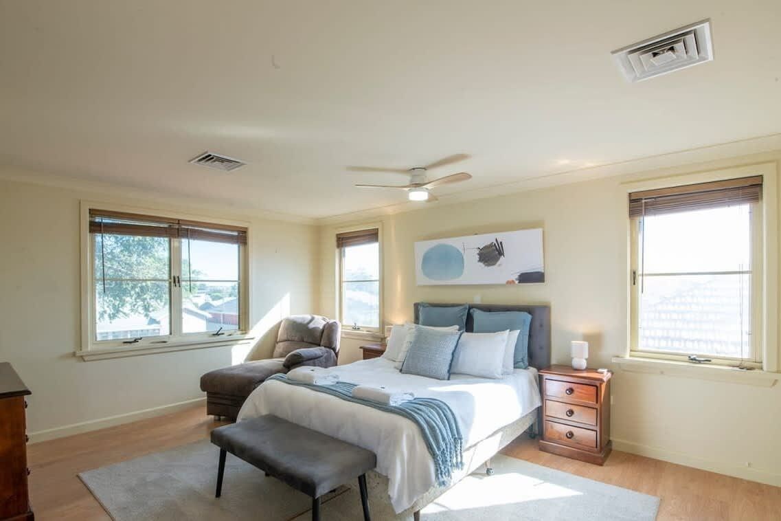 A bedroom with a bed, bedside table, chair, and a window.