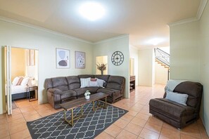 Un salon comprenant un canapé d’angle, une petite table et une horloge décorative accrochée au mur.
