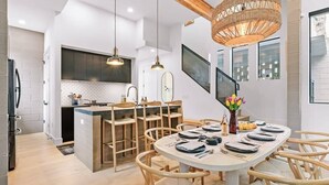 Une cuisine moderne dotée d’un îlot central, de chaises en bois et d’une table à manger pouvant accueillir six personnes.