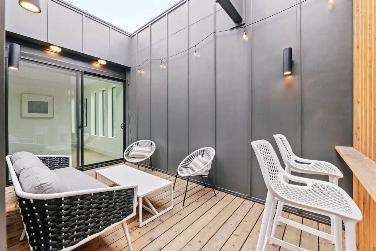 An outdoor patio with a sofa, two chairs, a small table, and string lights.