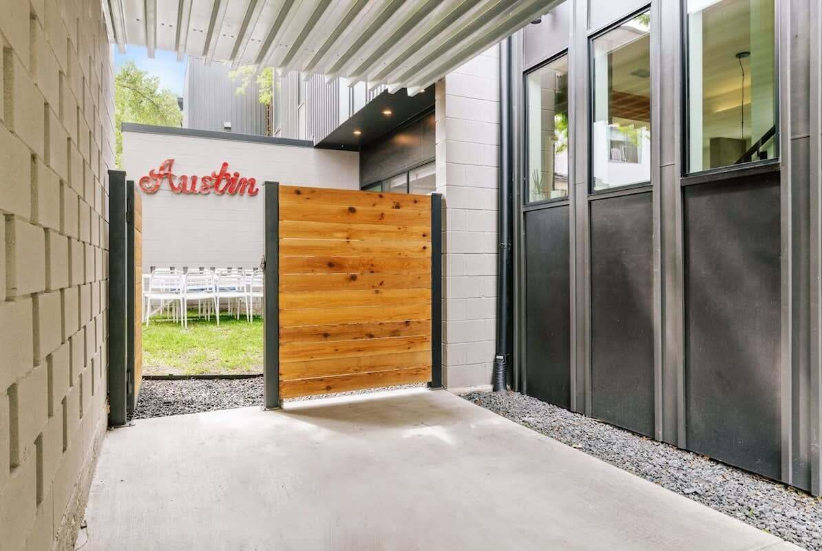 Entrada d'un edifici modern amb una porta de fusta, un rètol que diu 'Austin' i una zona exterior coberta.