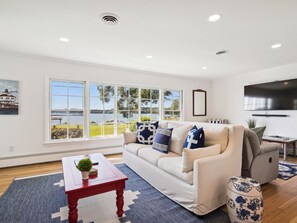 A modern living room with a large window, a sofa, a coffee table, and a TV.