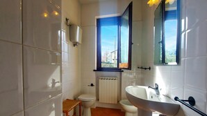 A bathroom with a toilet, sink, and window. - Casale Francesca With Private Pool (Bettona)