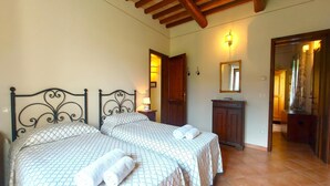 A bedroom with two beds, a wooden ceiling, a nightstand with a lamp, a mirror, and a wardrobe. - Casale Francesca With Private Pool (Bettona)