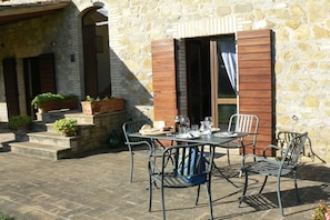 An outdoor patio with a table set for dining, surrounded by metal chairs.