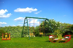 A playground with swings and a climbing structure in a grassy area.