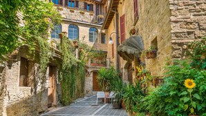 A narrow alley with stone buildings, a small table and chairs, and potted plants. - Casale Francesca With Private Pool (Bettona)