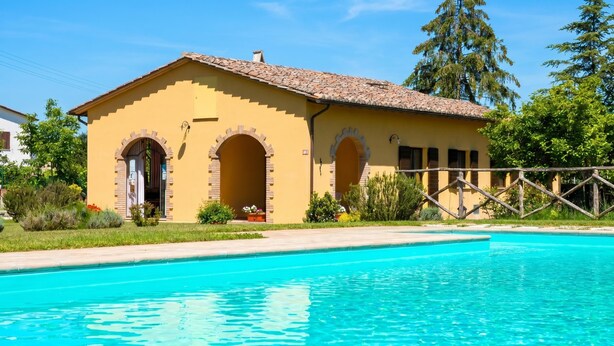 A yellow building with arched doorways, a swimming pool, and a wooden fence. - Casale Francesca With Private Pool (Bettona)