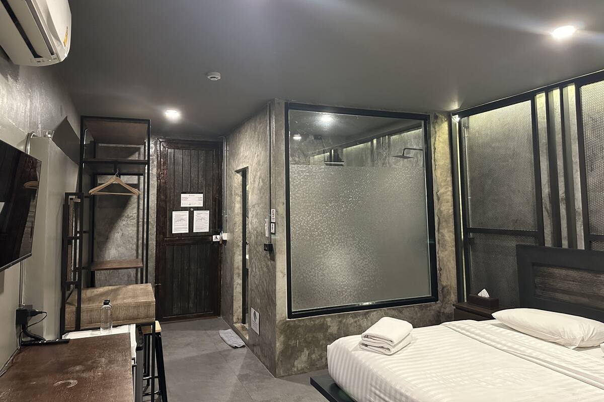 Ein modernes Hotelzimmer mit einem großen Bett, einer Duschkabine und einem Kleiderschrank.