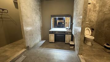 A bathroom with a marble floor, a sink with a mirror, and a toilet.
