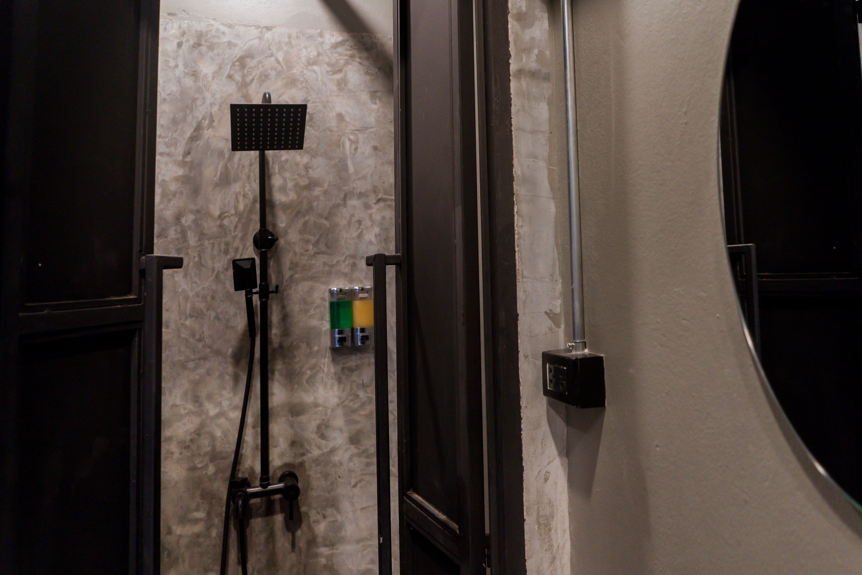 A bathroom with a shower, a towel rack, and a wall-mounted control panel.