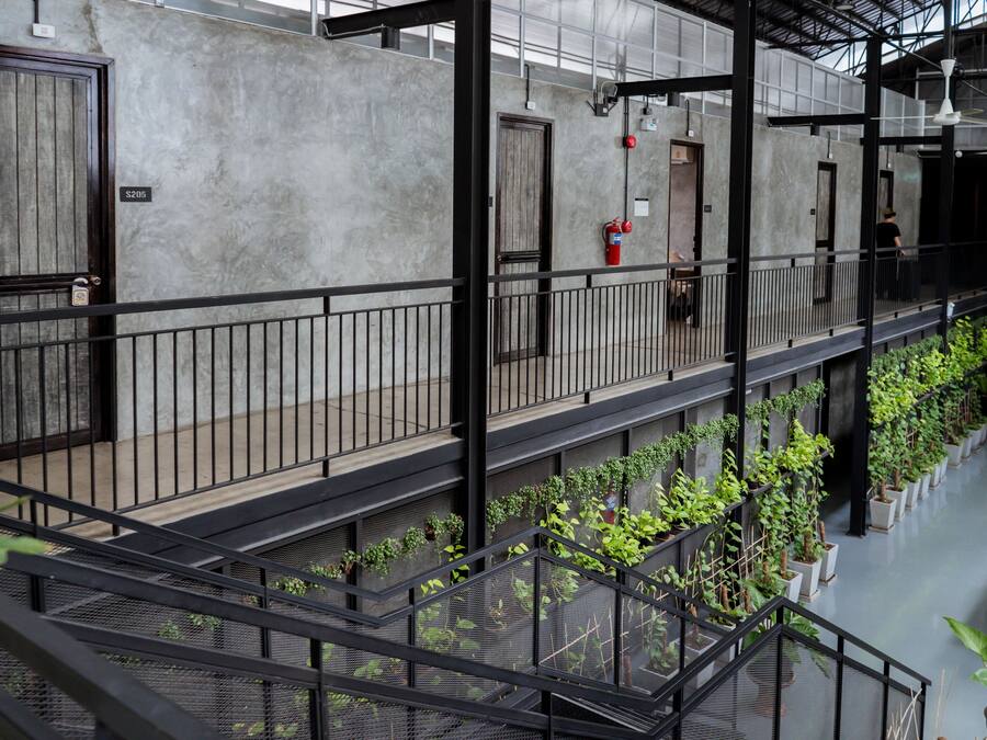 A multi-level interior with a metal railing, potted plants, and a fire extinguisher.