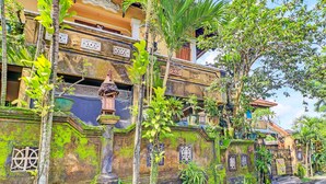 A traditional building with a stone facade, a thatched-roof structure, and lush greenery. - OYO 91235 Pondok Damu (Mengwi)