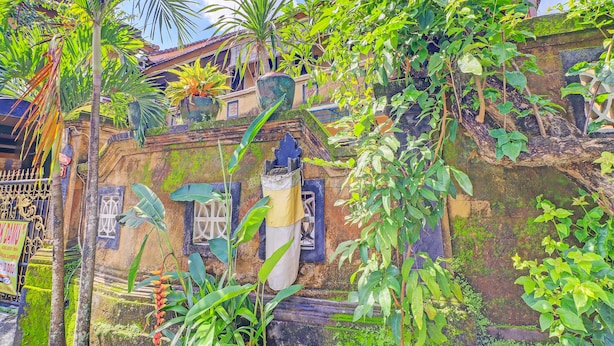 A traditional building with a stone facade, a tiled roof, and a variety of potted plants. - OYO 91235 Pondok Damu (Mengwi)