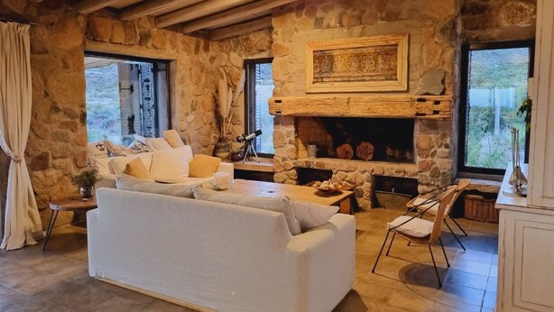 A rustic stone interior with a fireplace, white sofa, and a dining table.