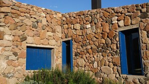 A stone building with two windows, one open, and a chimney.