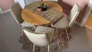 Una mesa redonda de madera con un posavasos tejido, rodeada por cuatro sillas con asientos acolchados.