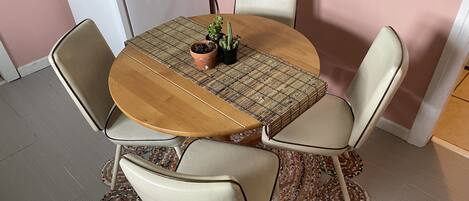 Una mesa redonda de madera con un posavasos tejido, rodeada por cuatro sillas con asientos acolchados.