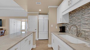 Una cocina moderna con armarios blancos, una isla central y un salpicadero de azulejos.