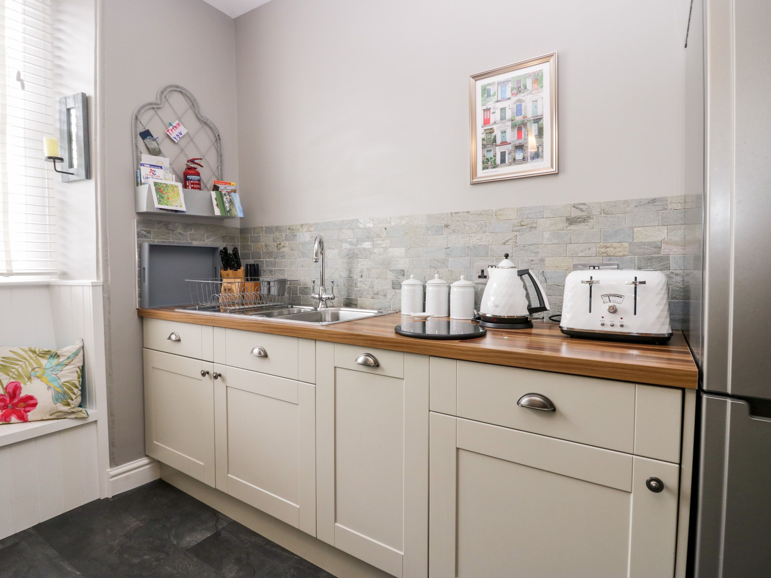 A kitchen with a stone backsplash, a stainless steel sink, and white appliances.