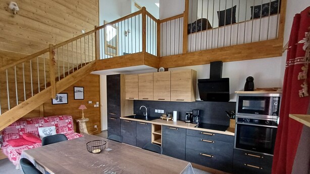Eine moderne Küche mit Holzausbau, einem Esstisch und einer Treppe, die in einen oberen Bereich führt.