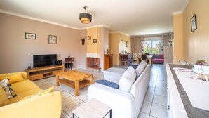 A living room with a TV, sofa, coffee table, fireplace, and dining area.
