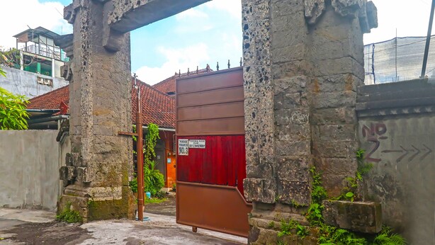 A stone archway leading to a building with a red gate. - Collection O 91684 Pondok SyariahNearMookiland Park Bali (Denpasar)