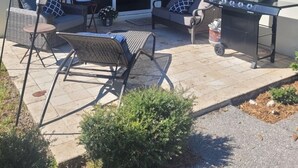 Eine Terrasse mit Gartenmöbeln, einem Grill und der Hausnummer 113.