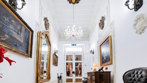 Un vaste hall d’entrée orné de miroirs aux cadres dorés, d’un lustre et de décorations murales de style classique.
