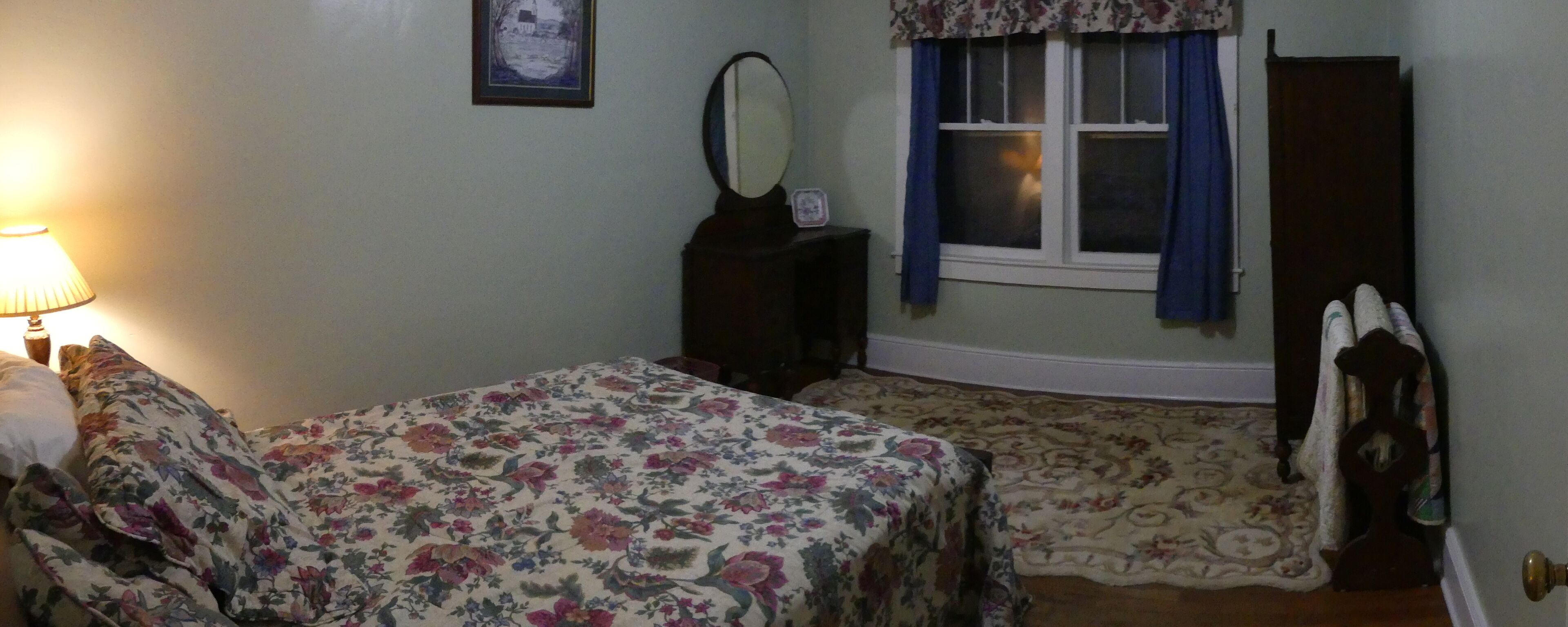 Een slaapkamer met twee bedden, een nachtkastje, een dressoir, een raam met gordijnen en een lamp.