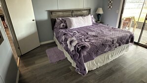 Une chambre à coucher avec un lit, une table de chevet, une lampe et une vue sur l’extérieur.