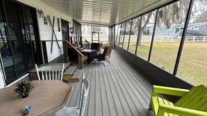 Un espace extérieur abrité, doté d’une terrasse en bois, d’une table avec des chaises et d’une chaise d’un vert vif.