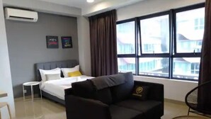 A hotel room with a bed, a black sofa, a small round table, and a window with a view of buildings. - Premium Suite Studio KLCC Arte+ (Kuala Lumpur)